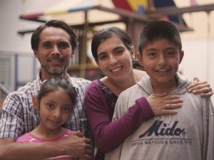 A latinx family smiling with two parents and two children