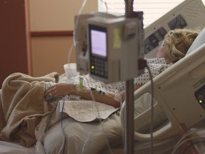 a white older adult woman in a hospital bed with machines monitoring her health